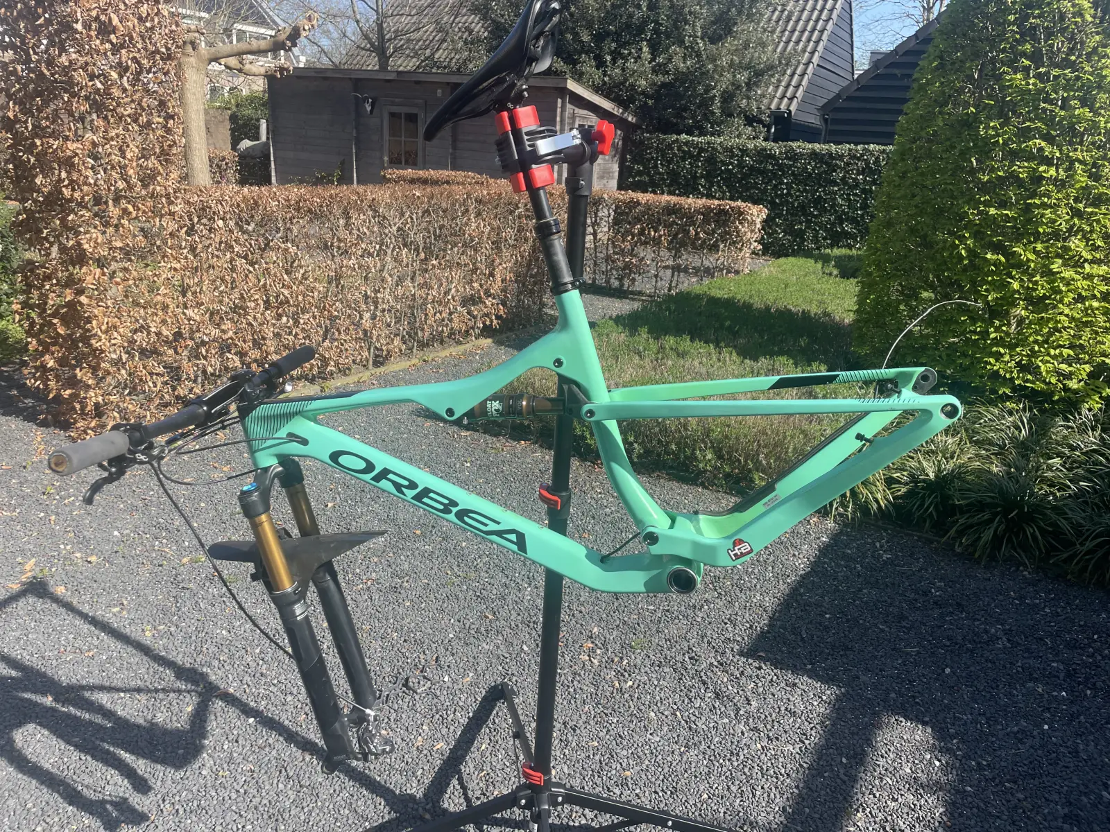Celeste green Orbea frame and fork stripped down on a workshop stand